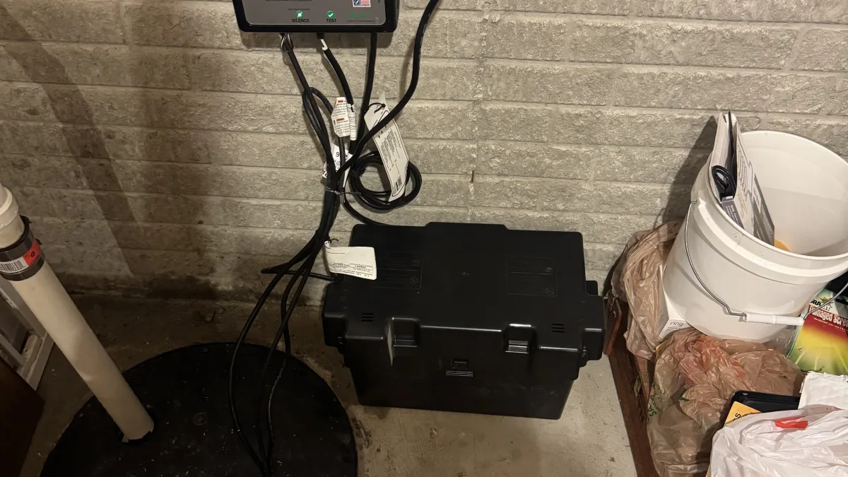 A sump pump installation area featuring a control unit, a battery backup box, and a sump basin during sump pump installation and repair in Lorain.