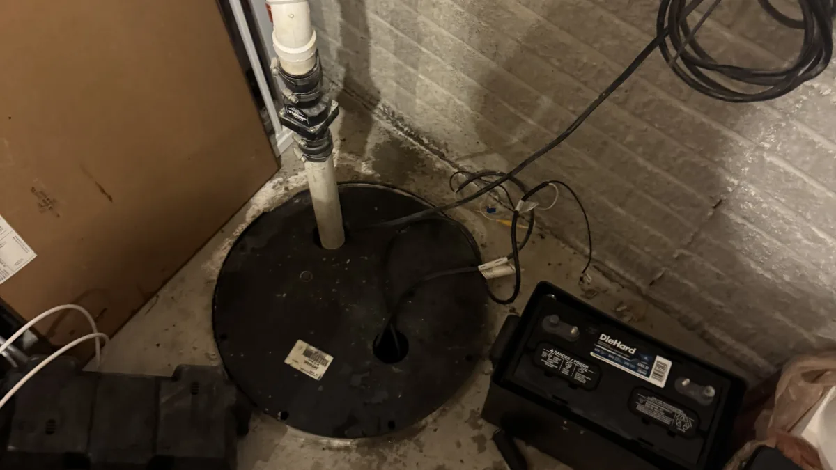 A sump pump installation area with a sump basin, battery backup system, and tools during sump pump installation and repair in Lorain.